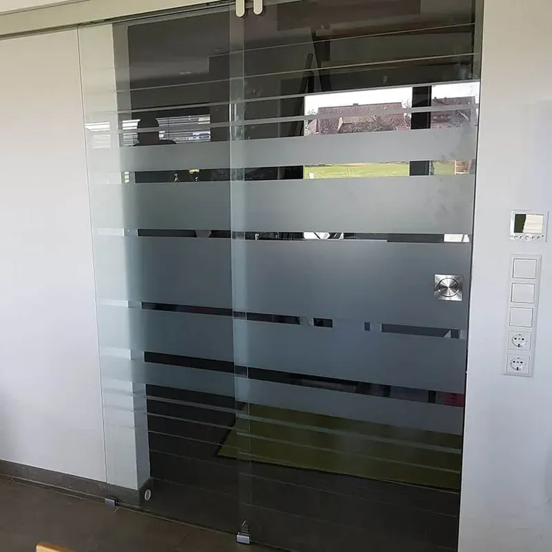 Glasschiebetür mit satinierten Streifen als Raumtrenner im Wohnbereich