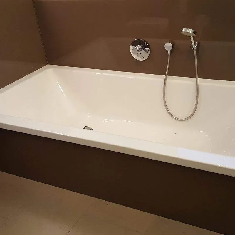 Badezimmerwand mit brauner Lackglas-Verkleidung rund um die Badewanne