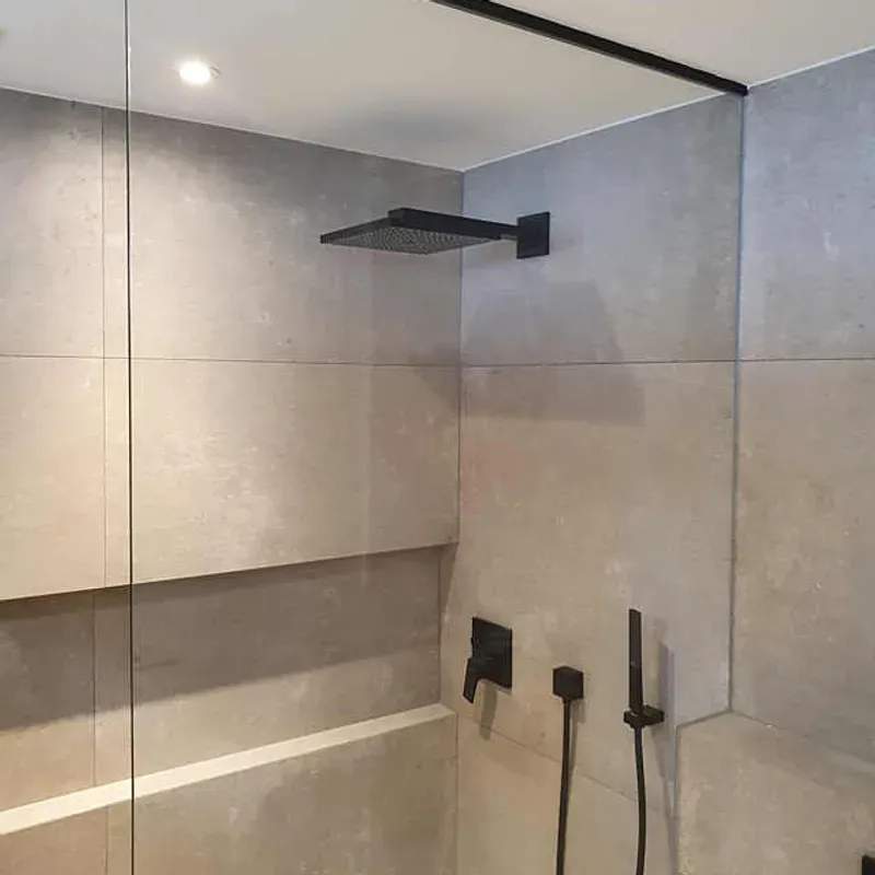 Rahmenlose Walk-in-Dusche mit Festverglasung und schwarzen Armaturen